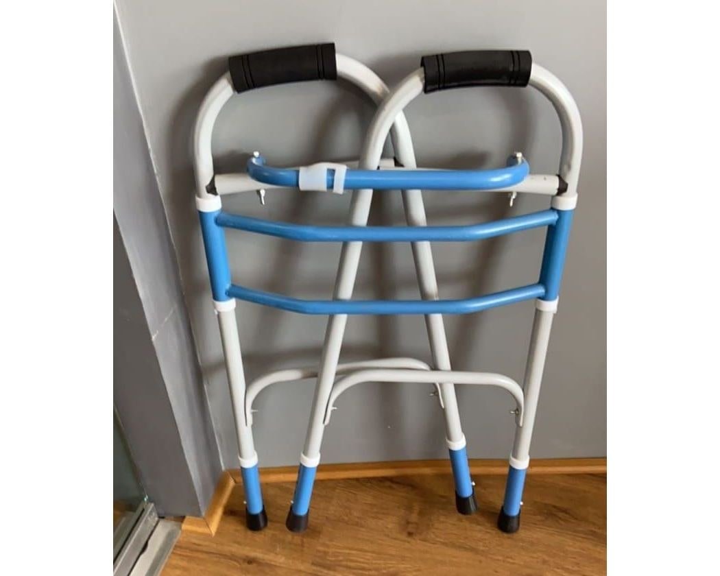 Folded blue and white walking frame with black hand grips