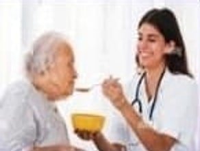 Nurse helping an elderly woman with her meal